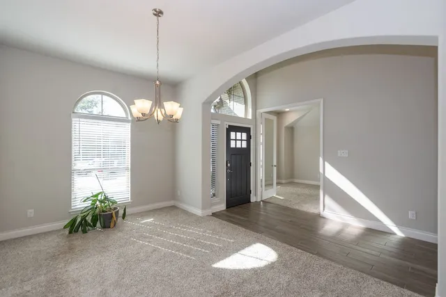 a view of a livingroom with a chandelier fan and windows