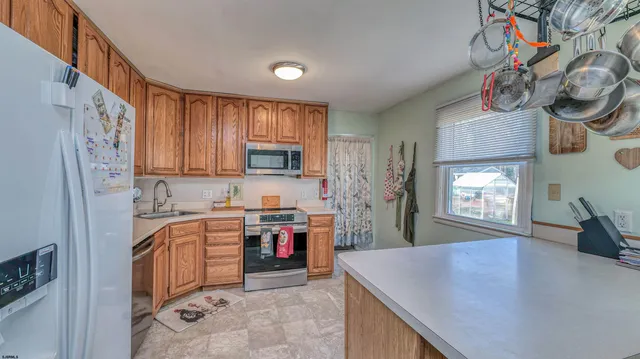 a kitchen with stainless steel appliances granite countertop a refrigerator a stove top oven a sink and dishwasher