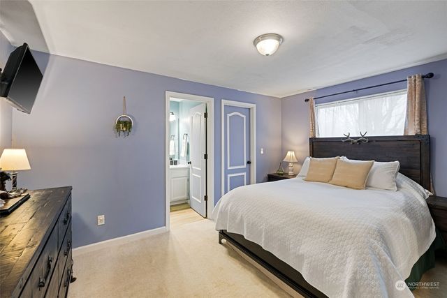 a bedroom with a bed and a flat tv screen on dresser