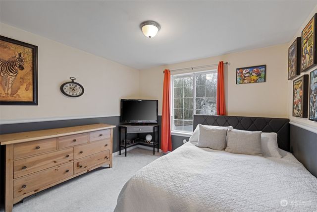 a bedroom with a bed and a flat tv screen on dresser