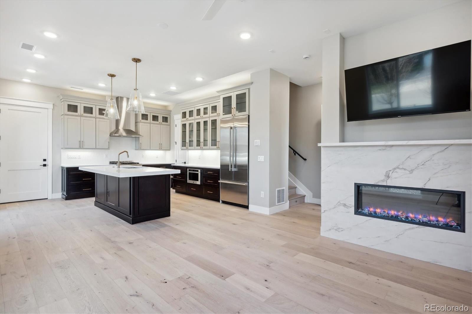 396 East Orchard Road Centennial, CO 80121 - Photo 5 of 34 a large kitchen with stainless steel appliances kitchen island granite countertop a large counter top and a sink with wooden floor