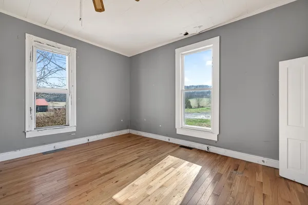 a view of an empty room with wooden floor fireplace and a window