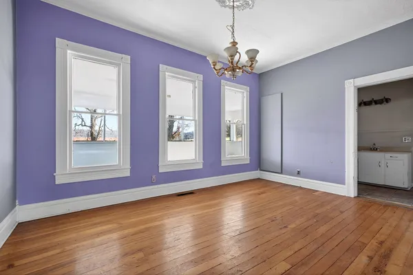 a view of an empty room with wooden floor fireplace and a window