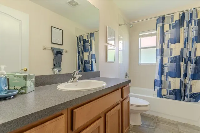 a bathroom with a granite countertop sink a toilet a mirror and shower