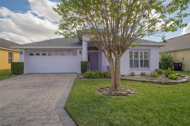 a front view of a house with a yard and tree