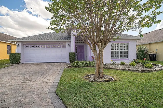 a front view of a house with a yard and tree