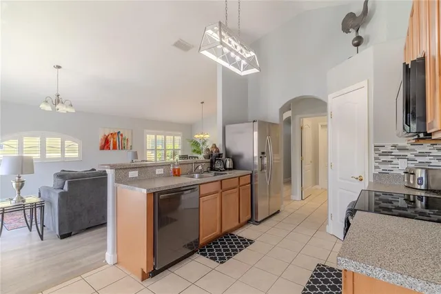 a kitchen with stainless steel appliances granite countertop a sink a stove oven a refrigerator with a dining table and chairs