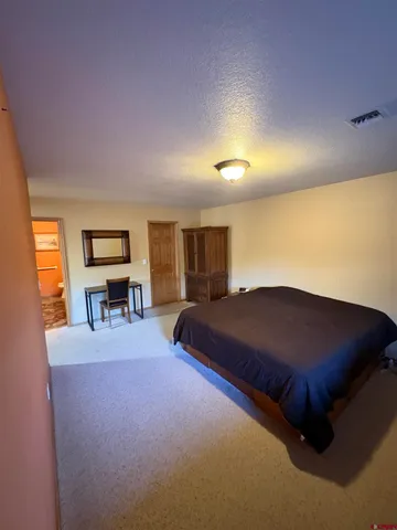 a bedroom with a bed and dresser with wooden floor