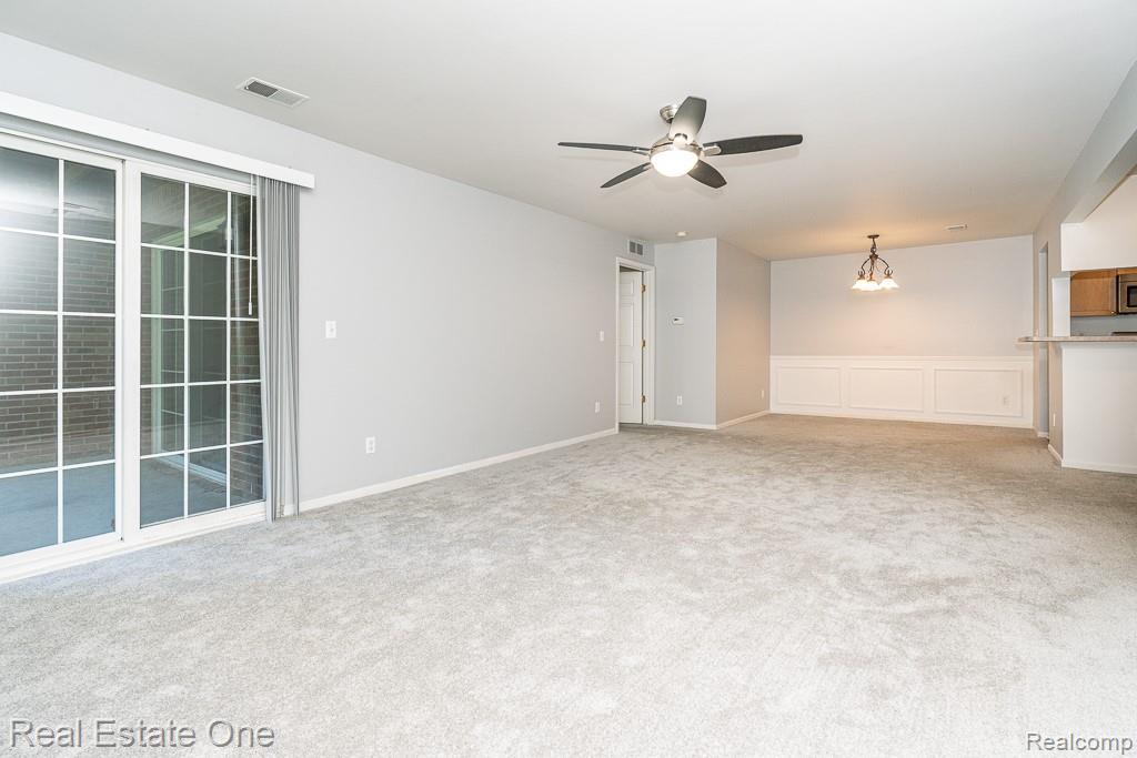 3491 Tremonte Circle Rochester, MI 48306 - Photo 7 of 42 Spacious interior with neutral carpeting, sliding patio doors, a ceiling fan, and wainscoting in the dining area