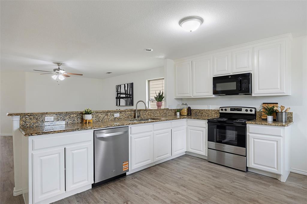 1605 Village Park Trail Burleson, TX 76028 - Photo 11 of 29 Kitchen with appliances with stainless steel finishes, white cabinets, light wood-style floors, dark stone counters, and a peninsula