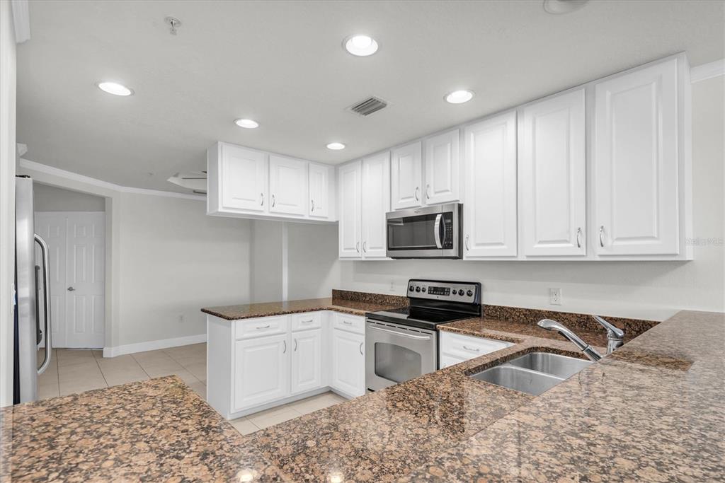 7069 Key Haven Road, Unit 302 Seminole, FL 33777 - Photo 12 of 65 a kitchen with stainless steel appliances granite countertop a sink a stove a refrigerator and cabinets