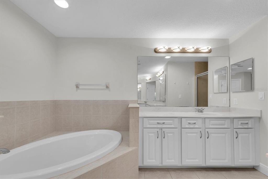 7069 Key Haven Road, Unit 302 Seminole, FL 33777 - Photo 26 of 65 a bathroom with a granite countertop bathtub a double vanity sink and a mirror