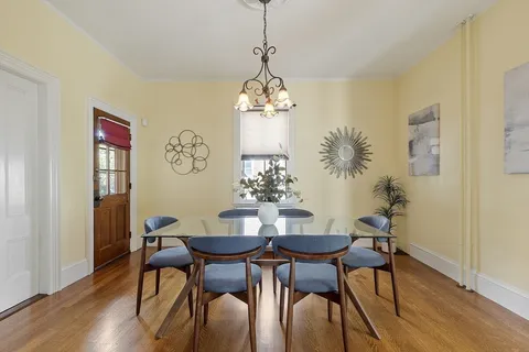 a dining room with wooden floor a chandelier a wooden table and chairs