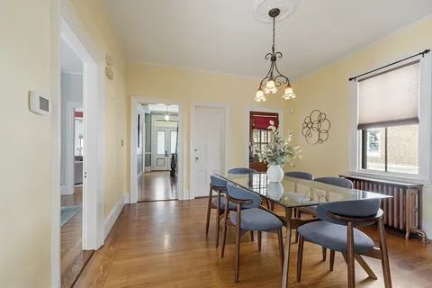 a dining room with wooden floor a chandelier a wooden table and chairs