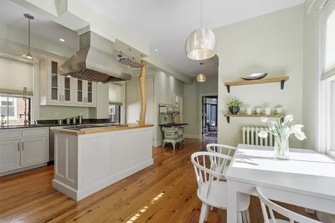 a kitchen with stainless steel appliances kitchen island granite countertop a table chairs in it and wooden floors