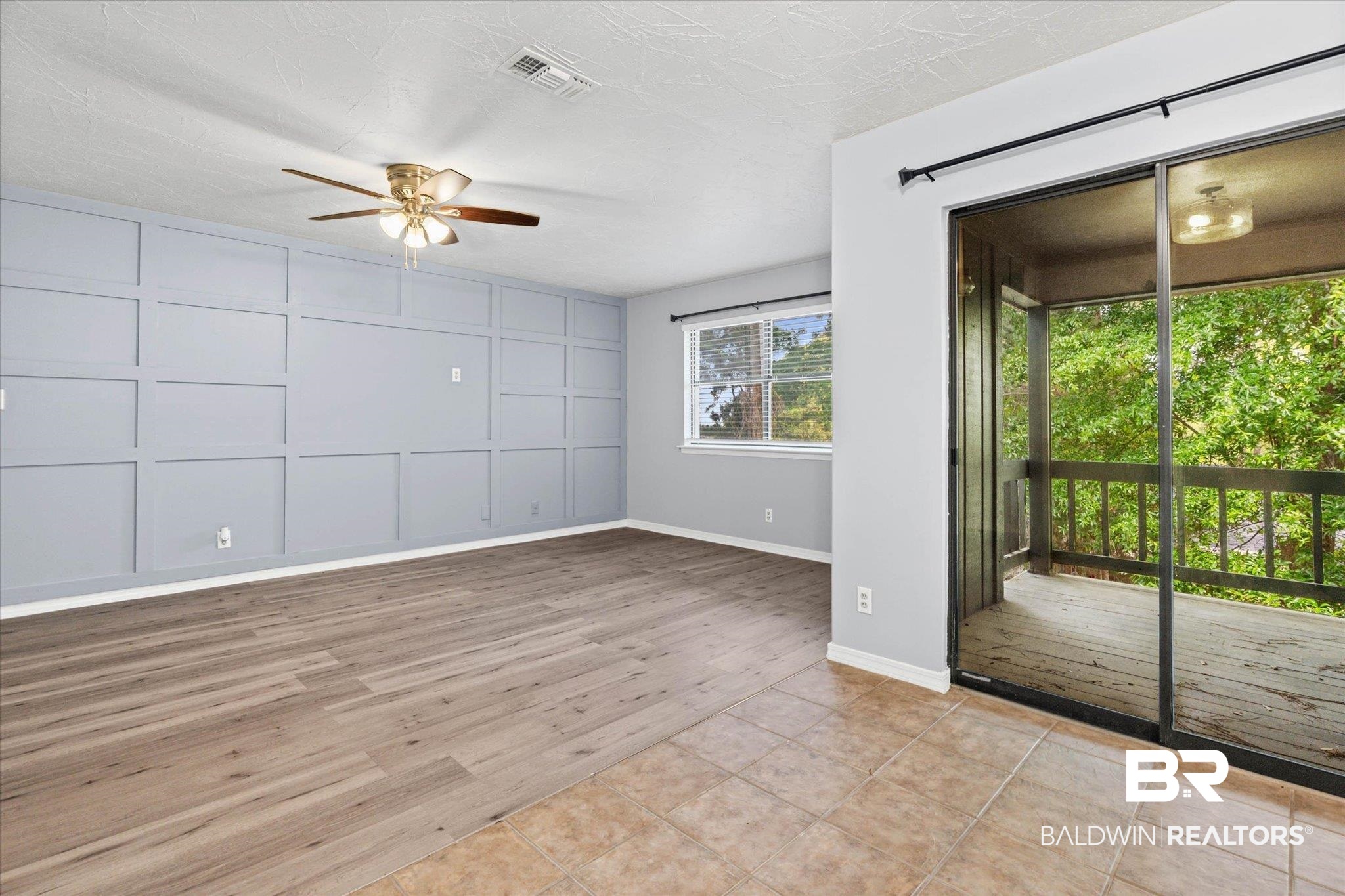 500 Grant Street, Unit C210 Daphne, AL 36526 - Photo 6 of 26 Living area featuring wood-finish flooring transitioning to tile, a custom accent wall, and a ceiling fan