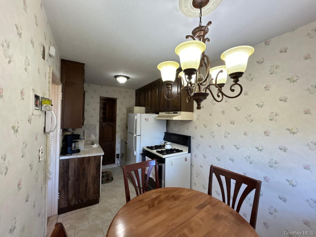 17-15 160th Street, Unit 594 Queens, NY 11357 - Photo 16 of 24 a dining room with stainless steel appliances furniture a chandelier and a window