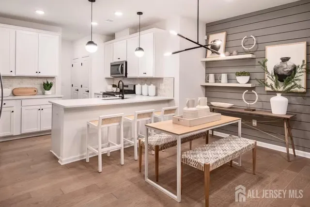 a kitchen with kitchen island a dining table chairs sink and cabinets
