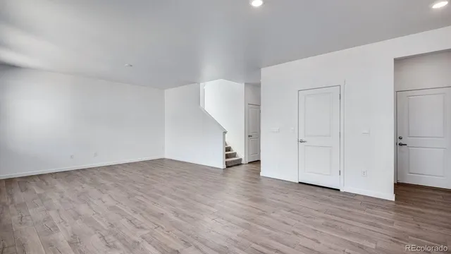 a view of an empty room with wooden floor and a hallway
