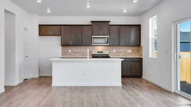 a kitchen with kitchen island wooden cabinets and refrigerator