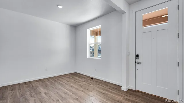 a view of an empty room with wooden floor and a window
