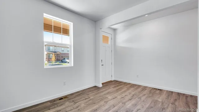 a view of an empty room with wooden floor and a window