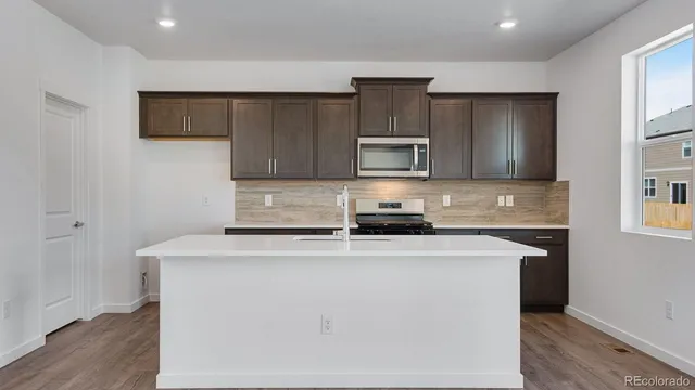 a kitchen with kitchen island a sink a stove a microwave and wooden cabinets