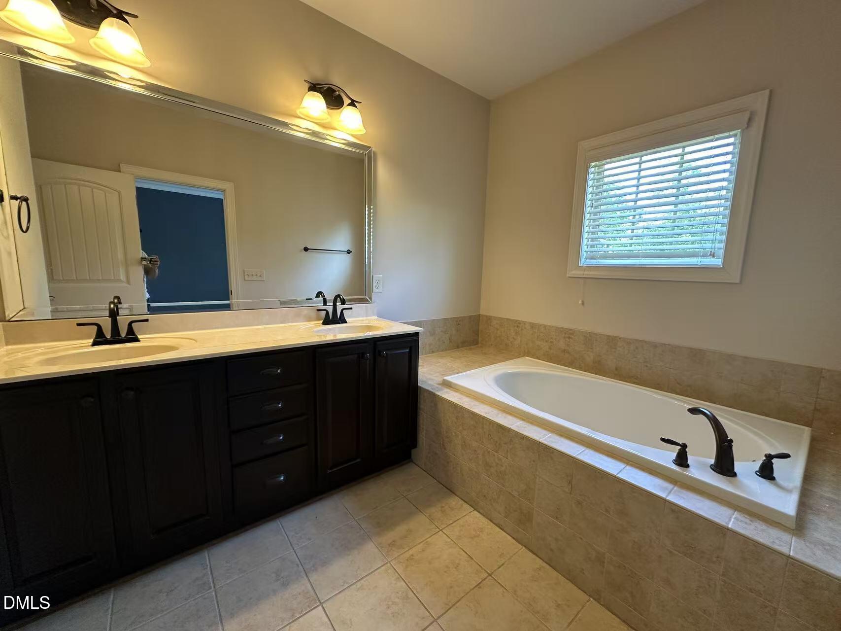 1056 Indigo Ridge Place Cary, NC 27519 - Photo 18 of 33 a bathroom with a tub sink and mirror