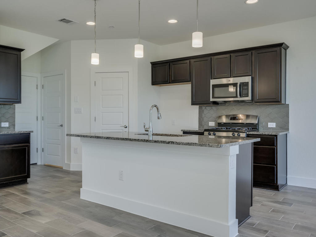 12327 Maypole Bend Austin, TX 78717 - Photo 11 of 30 a kitchen with stainless steel appliances granite countertop a stove a sink and a microwave