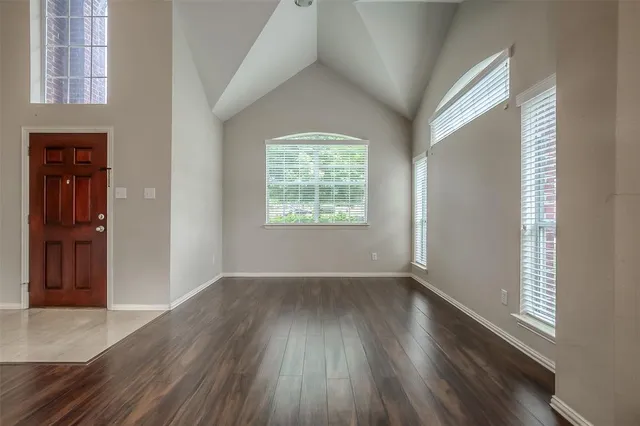 an empty room with wooden floor closet and windows