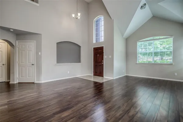 an empty room with wooden floor mirror and windows