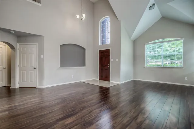 an empty room with wooden floor mirror and windows