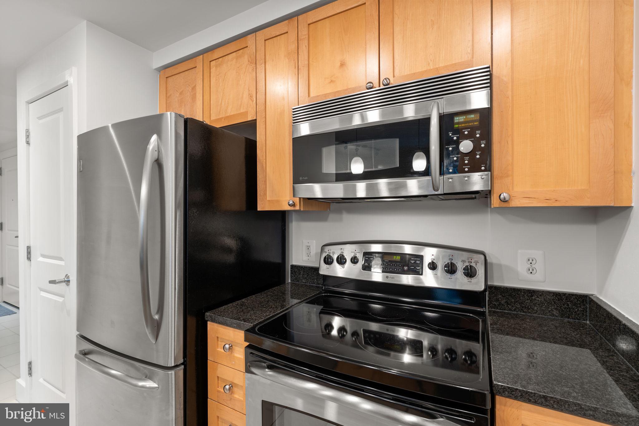 2001 15th Street North, Unit 813 Arlington, VA 22201 - Photo 12 of 31 a kitchen with stainless steel appliances wooden cabinets and a stove top oven