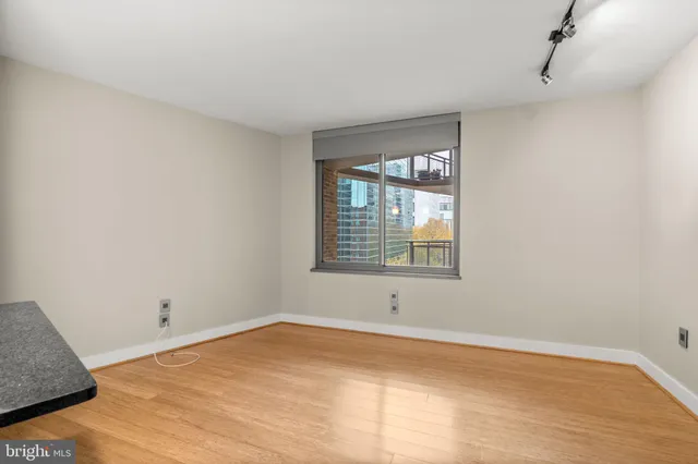 a view of an empty room with wooden floor and a window