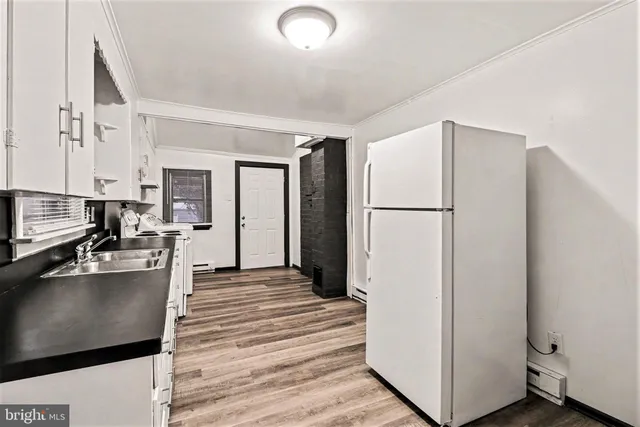 a kitchen with a refrigerator a stove and white cabinets with wooden floor