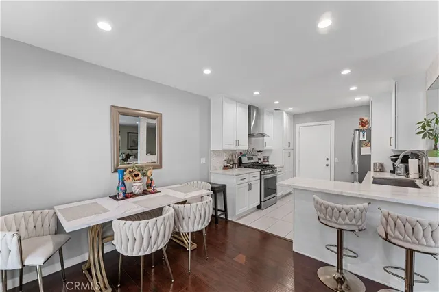 a kitchen with kitchen island granite countertop a dining table chairs refrigerator and cabinets