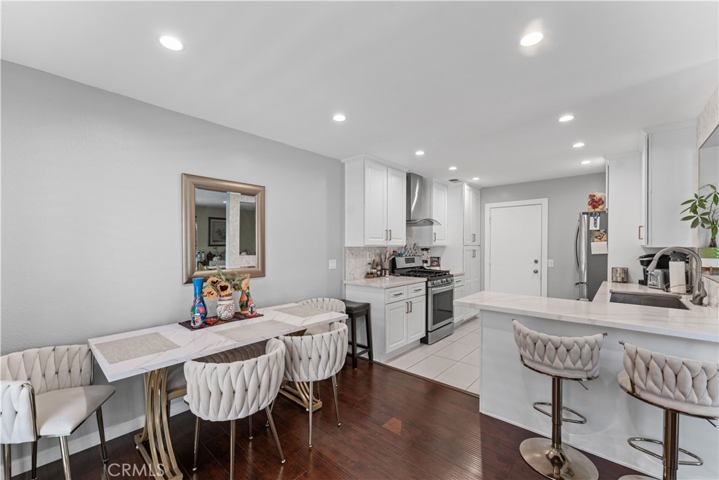 12331 Carl Street Pacoima, CA 91331 - Photo 9 of 28 a kitchen with kitchen island granite countertop a dining table chairs refrigerator and cabinets