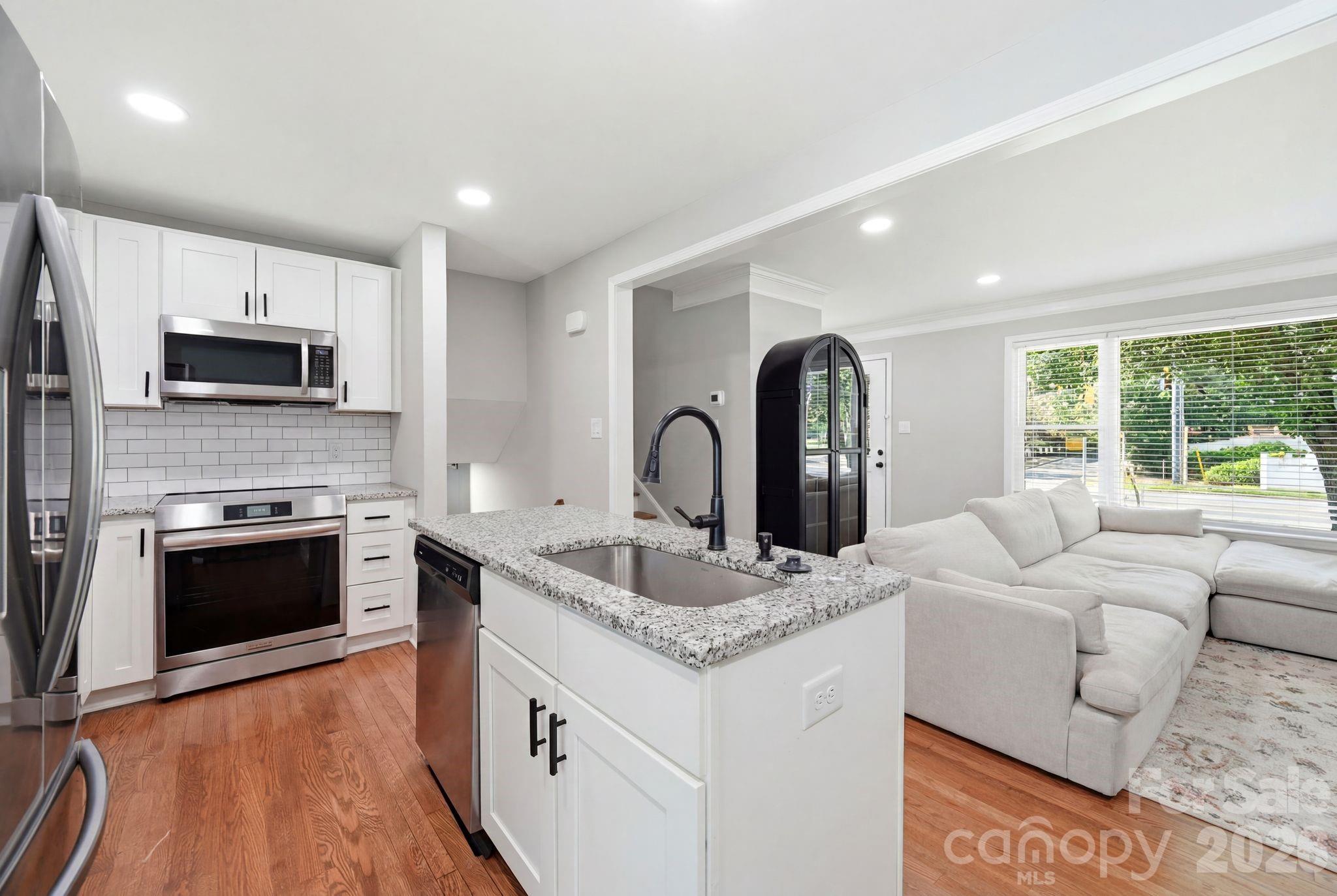 7552 Idlewild Road Charlotte, NC 28212 - Photo 6 of 40 a living room with stainless steel appliances granite countertop a sink and a stove top oven with wooden floor