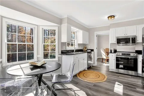 a kitchen with sink a stove a dining table and chairs