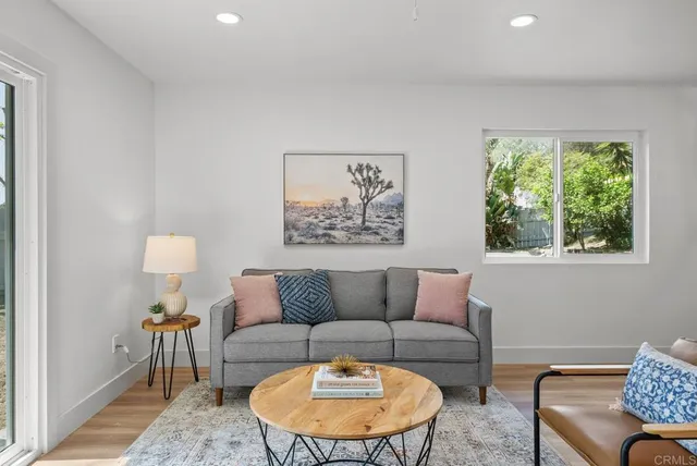 a kitchen with stainless steel appliances kitchen island granite countertop a refrigerator a stove a dining table and chairs with wooden floor