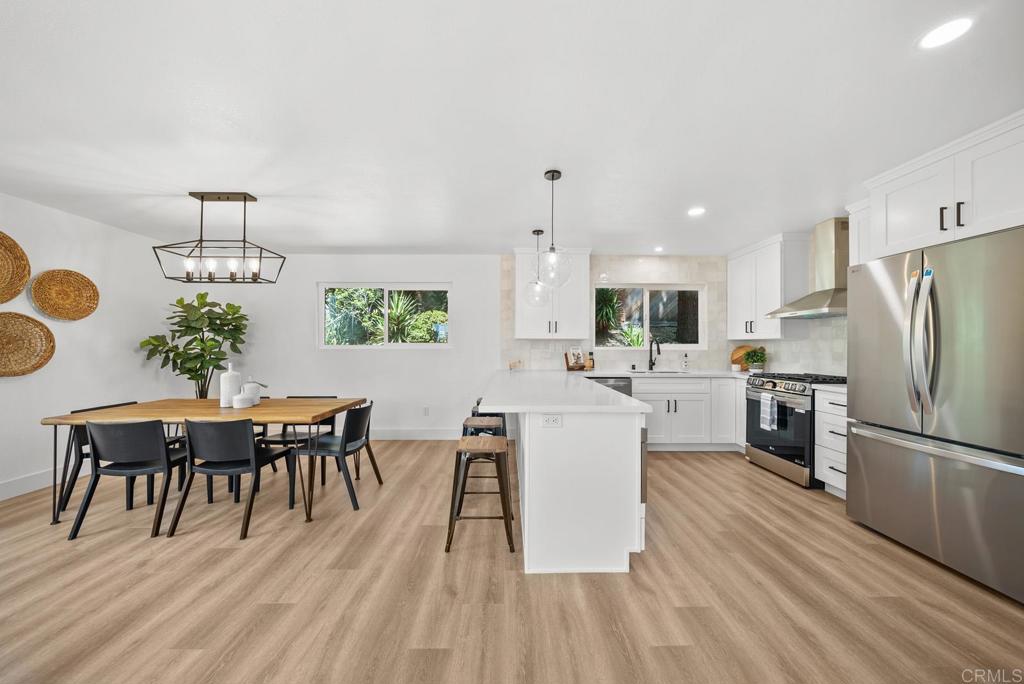 9306 Hollyhock Lane Spring Valley, CA 91977 - Photo 24 of 61 a kitchen with stainless steel appliances kitchen island granite countertop a refrigerator a stove a dining table and chairs with wooden floor