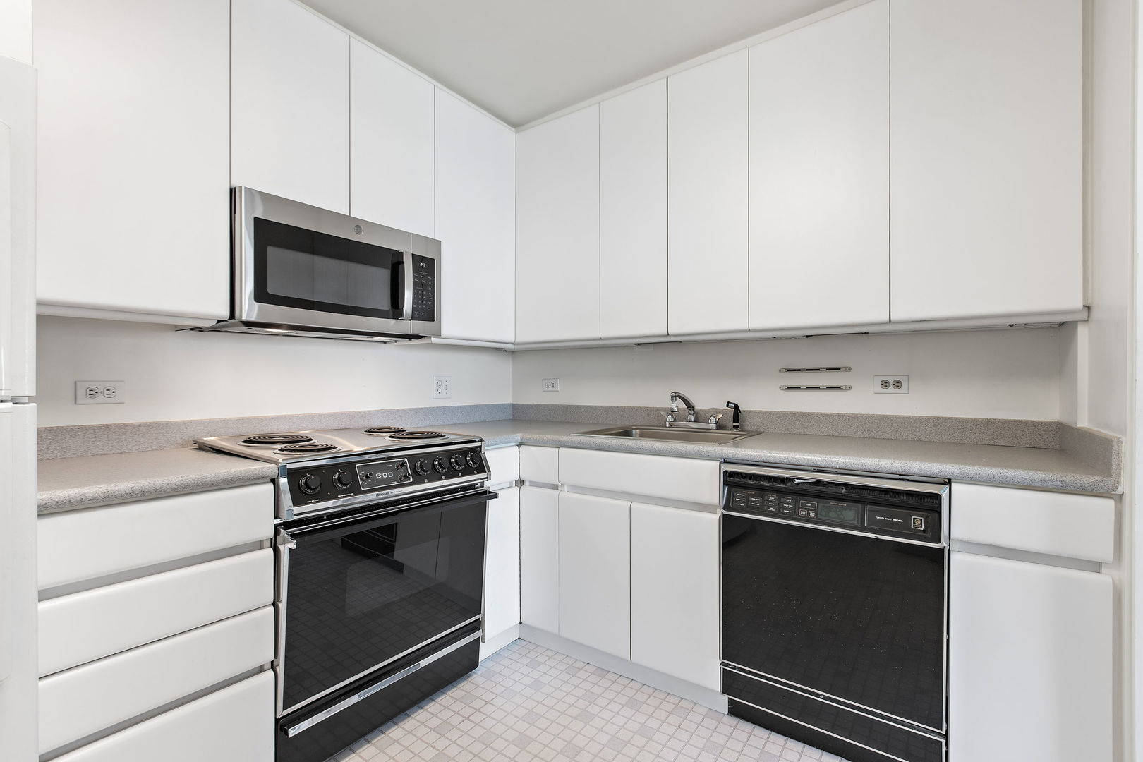 5445 North Sheridan Road, Unit 2810 Chicago, IL 60640 - Photo 8 of 17 a kitchen with granite countertop white cabinets and stainless steel appliances