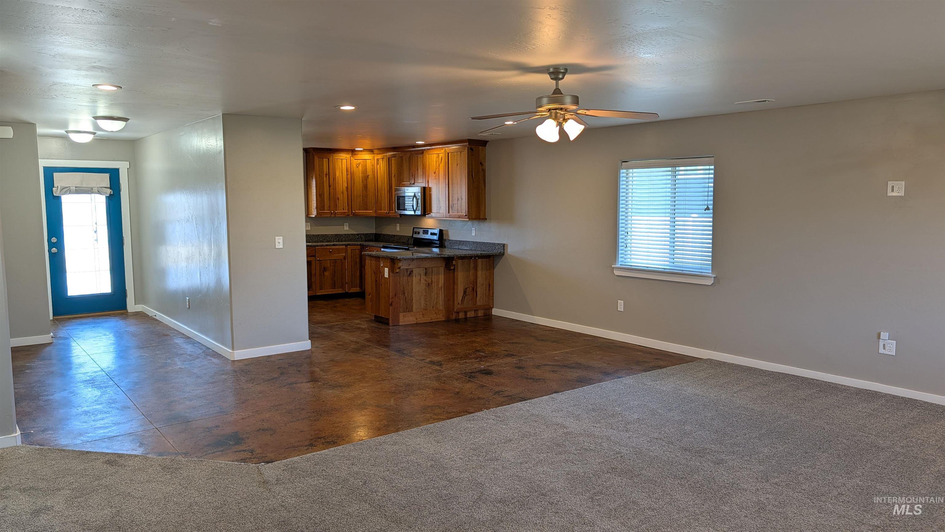 622 Lochsa Loop Heyburn, ID 83336 - Photo 3 of 17 Open-concept living space featuring wood-finish flooring, a kitchen with rich wood cabinetry and dark countertops, and a ceiling fan