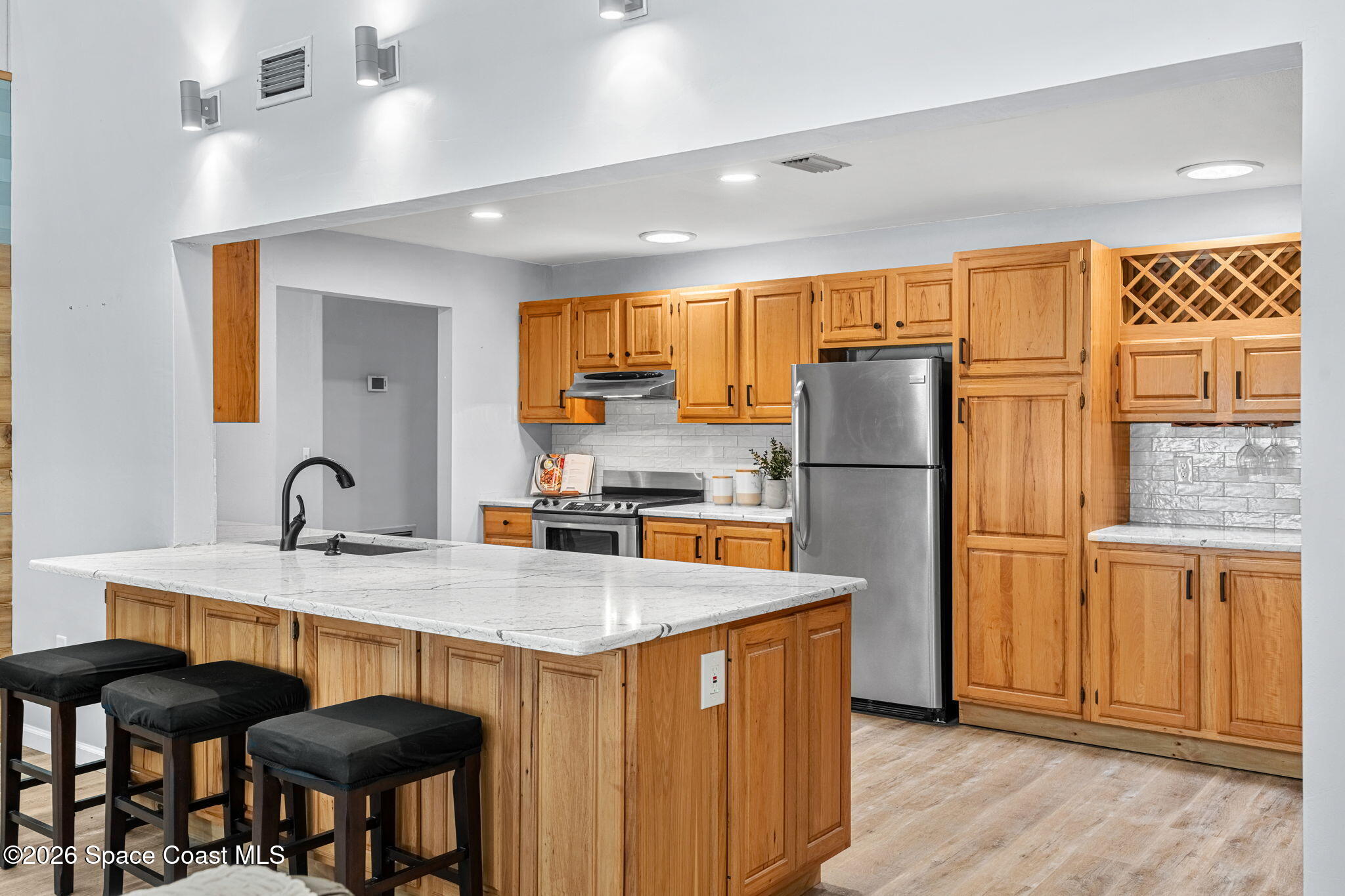 975 Oak Street Merritt Island, FL 32953 - Photo 12 of 76 a kitchen with stainless steel appliances granite countertop a refrigerator a sink dishwasher a stove with chairs and wooden floor