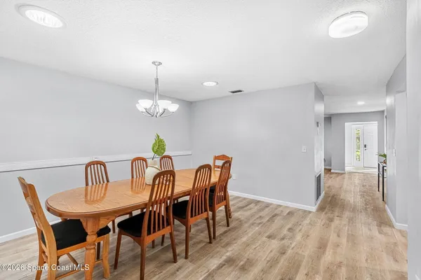 a dining room with furniture a chandelier and wooden floor