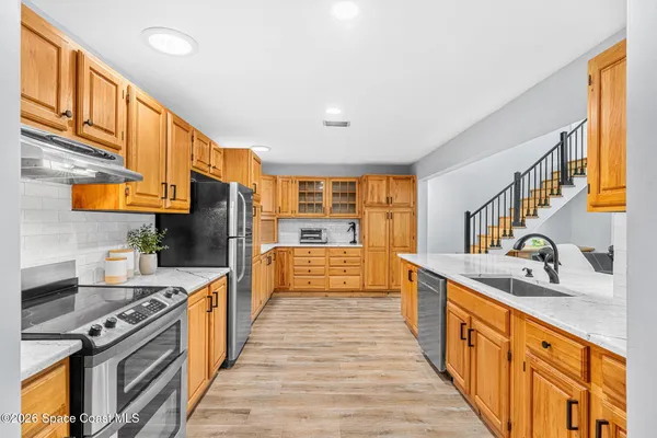 a kitchen with a stove a refrigerator and wooden cabinets