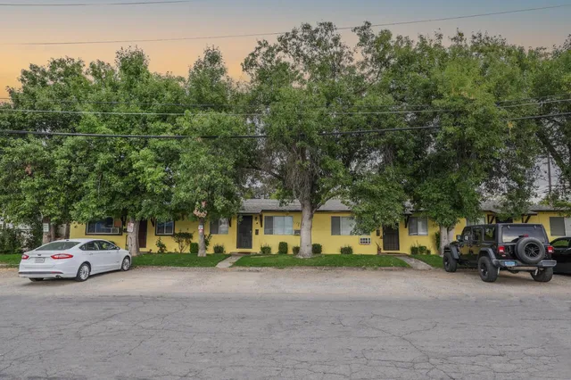 a view of road with card parked on side and retail shops