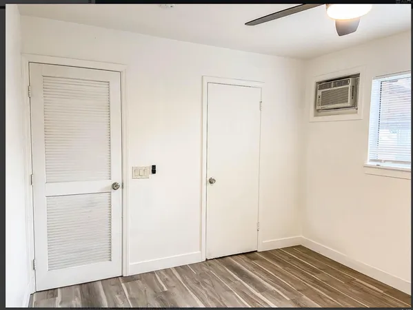 a view of an empty room with window and wooden floor