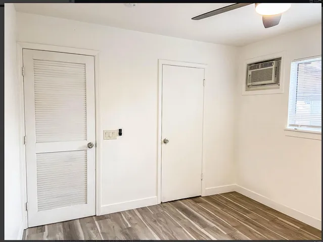 a view of an empty room with window and wooden floor