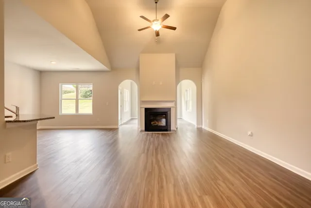 a view of a livingroom with a fireplace a ceiling fan and wooden floor